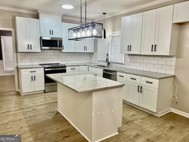 kitchen with a kitchen island, decorative light fixtures, light stone countertops, stainless steel appliances, and white cabinetry