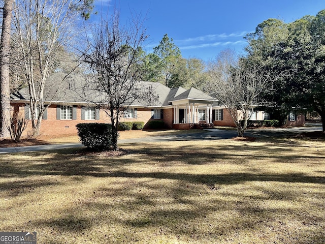 view of front facade featuring brick siding, crawl space, and a front yard