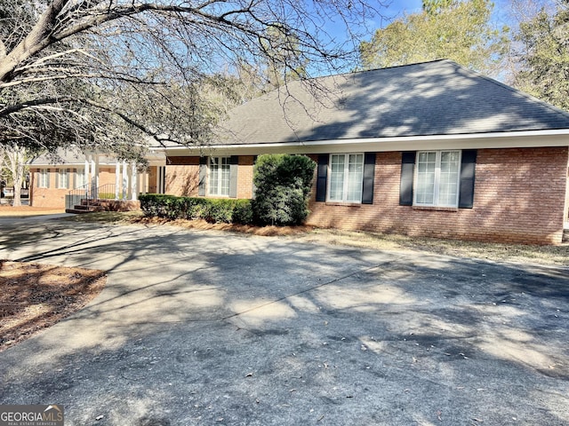 view of front of property with brick siding and roof with shingles