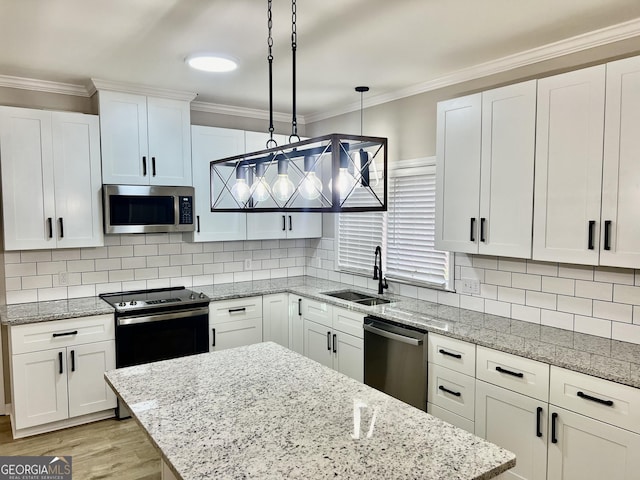 kitchen with appliances with stainless steel finishes, pendant lighting, white cabinetry, and a sink