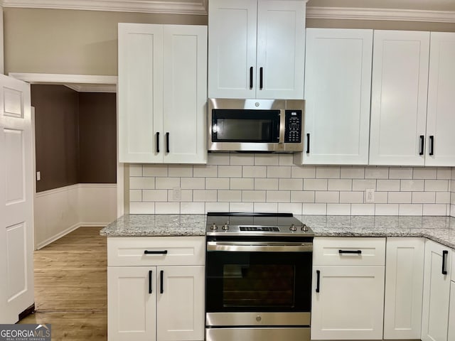 kitchen featuring stainless steel appliances, white cabinetry, and light stone countertops