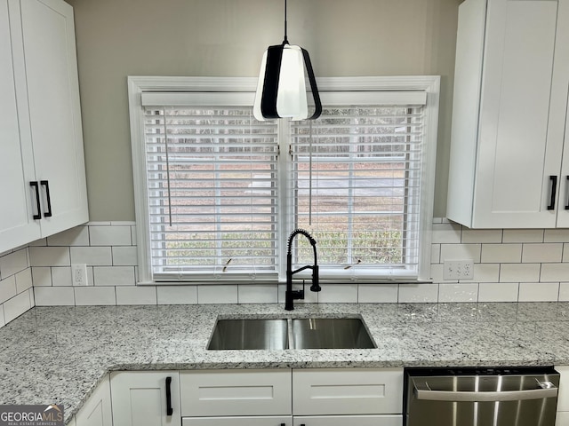 kitchen featuring a sink, white cabinets, hanging light fixtures, stainless steel dishwasher, and backsplash