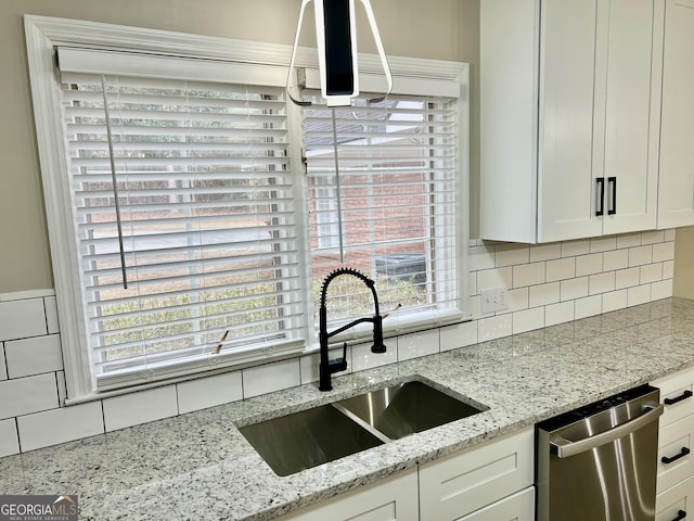 kitchen with white cabinetry, dishwasher, a sink, and light stone countertops