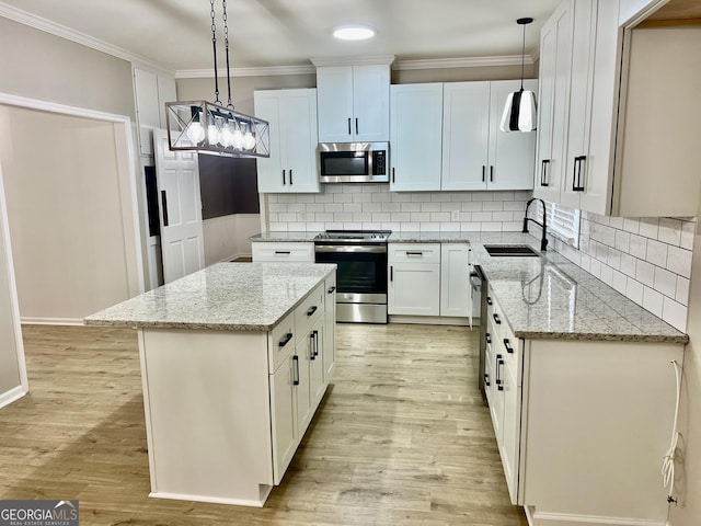 kitchen featuring appliances with stainless steel finishes, white cabinets, and decorative light fixtures