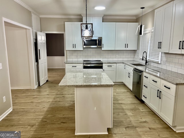 kitchen featuring a kitchen island, hanging light fixtures, stainless steel appliances, white cabinetry, and a sink