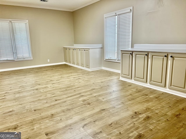 unfurnished room featuring plenty of natural light, light wood finished floors, baseboards, and ornamental molding