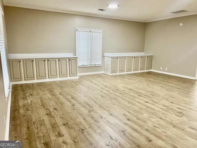 unfurnished room with light wood-type flooring, visible vents, crown molding, and baseboards