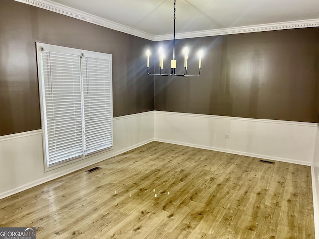 unfurnished dining area with ornamental molding, a chandelier, visible vents, and wood finished floors