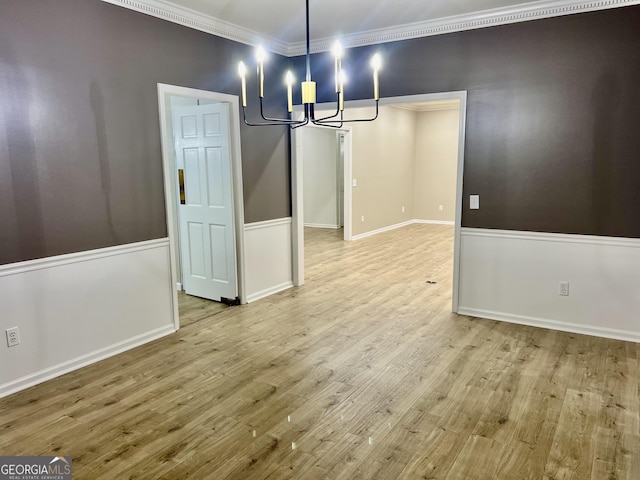 unfurnished dining area with light wood finished floors, a notable chandelier, baseboards, and crown molding