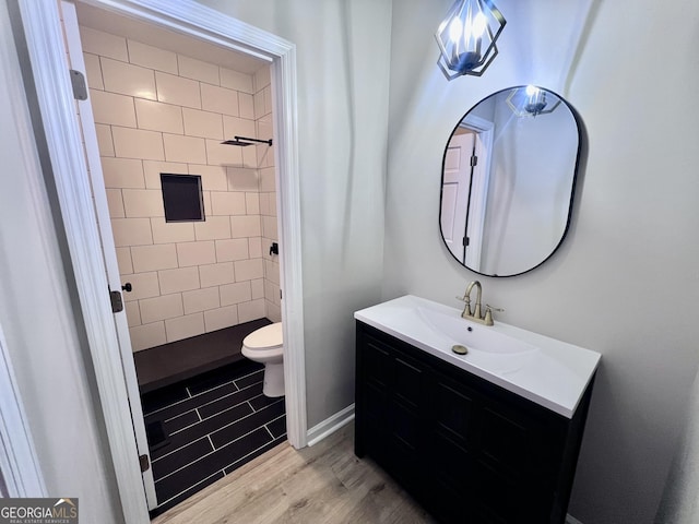 full bathroom featuring toilet, vanity, a shower stall, wood finished floors, and baseboards