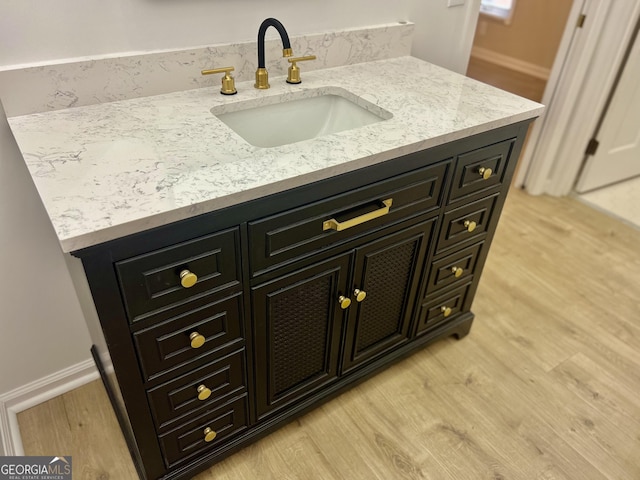 bathroom with wood finished floors, vanity, and baseboards