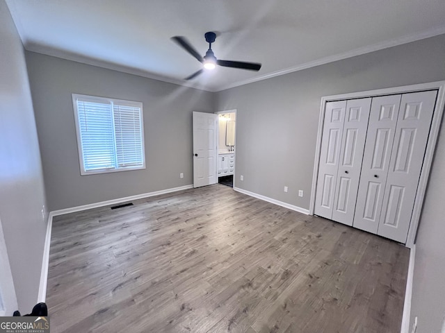 unfurnished bedroom with visible vents, crown molding, baseboards, and wood finished floors