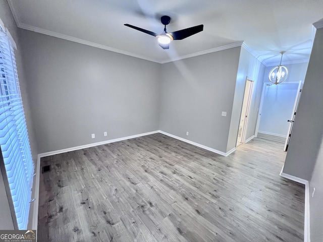 empty room with ceiling fan with notable chandelier, visible vents, baseboards, and wood finished floors