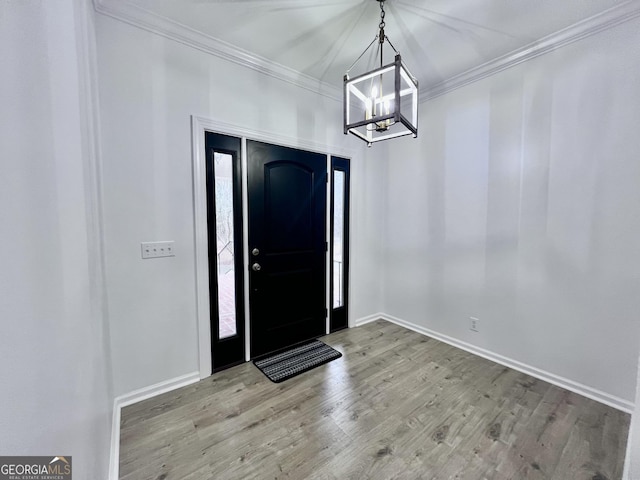 entrance foyer with baseboards, a chandelier, wood finished floors, and crown molding