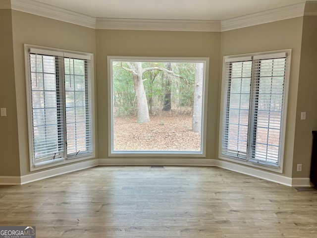 unfurnished dining area featuring visible vents, baseboards, light wood-style flooring, and crown molding