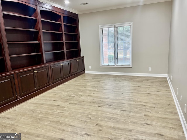 empty room with baseboards, light wood-type flooring, and crown molding