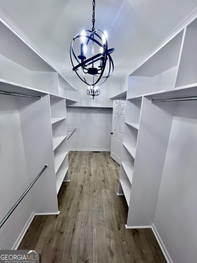 walk in closet featuring wood finished floors and an inviting chandelier