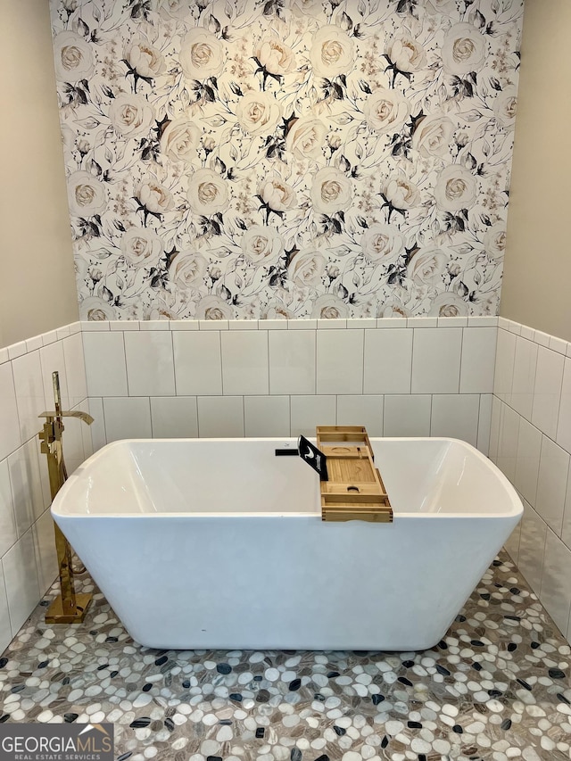 bathroom featuring a freestanding bath, wainscoting, and wallpapered walls