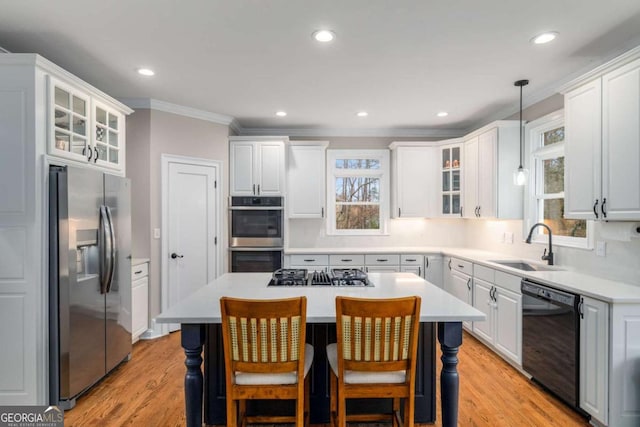 kitchen featuring pendant lighting, sink, stainless steel appliances, a kitchen breakfast bar, and a kitchen island