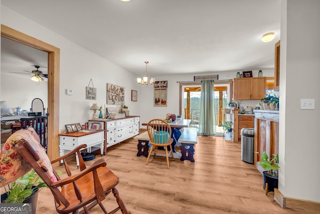 dining room with ceiling fan with notable chandelier and light wood-type flooring