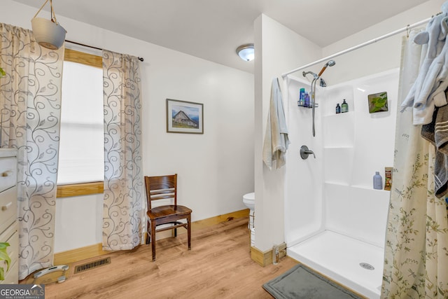 bathroom with toilet, a shower with shower curtain, and hardwood / wood-style floors