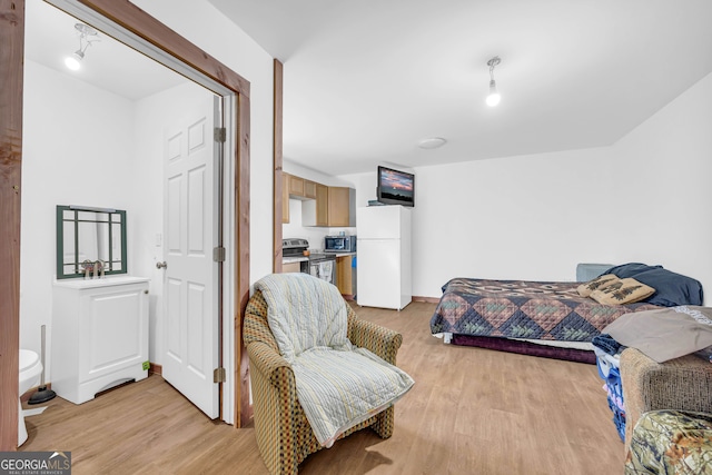 bedroom featuring light wood-type flooring and white refrigerator