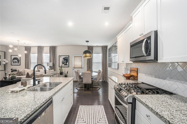 kitchen featuring sink, white cabinetry, hanging light fixtures, stainless steel appliances, and light stone counters