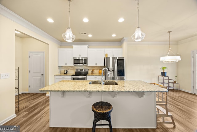 kitchen featuring light stone counters, stainless steel appliances, a kitchen breakfast bar, and white cabinets