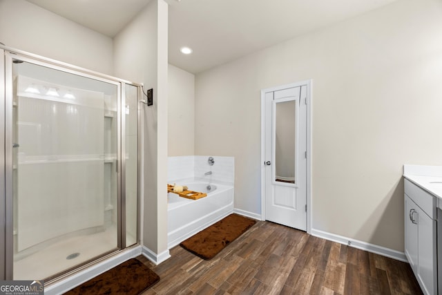 bathroom with wood-type flooring, vanity, and plus walk in shower