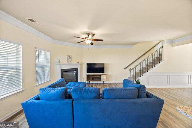 living room with hardwood / wood-style floors, crown molding, and ceiling fan