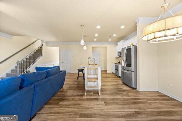 kitchen with appliances with stainless steel finishes, decorative light fixtures, white cabinetry, a breakfast bar area, and a kitchen island with sink