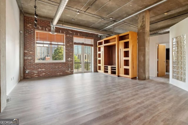 unfurnished living room with brick wall and wood-type flooring