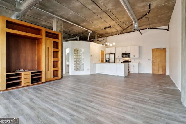 unfurnished living room featuring light hardwood / wood-style floors and a high ceiling