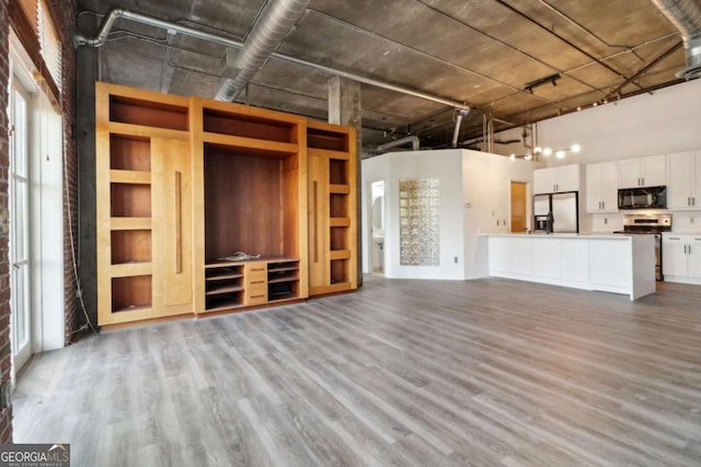 unfurnished living room featuring hardwood / wood-style flooring and a towering ceiling