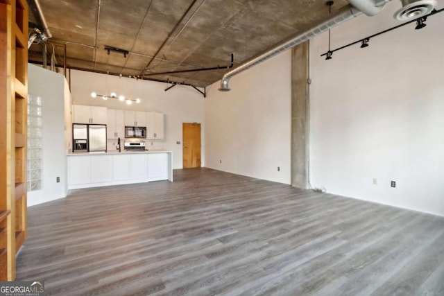 unfurnished living room featuring wood-type flooring and a high ceiling