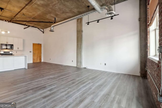 unfurnished living room featuring a towering ceiling and wood-type flooring