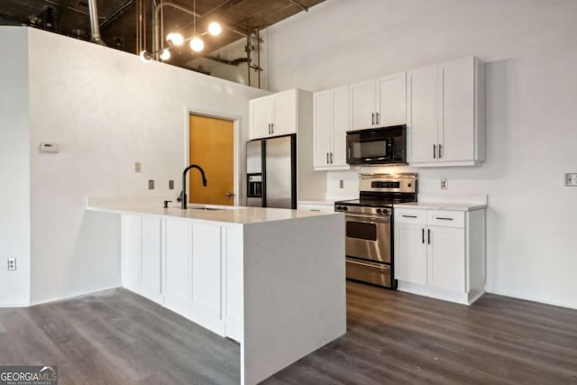 kitchen featuring stainless steel appliances, white cabinetry, sink, and a high ceiling