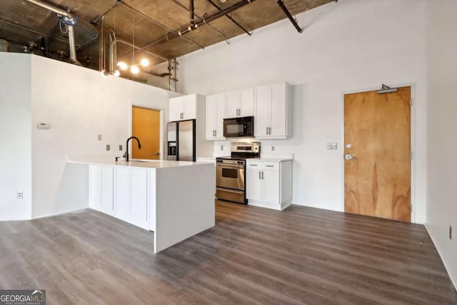 kitchen with dark wood-type flooring, sink, white cabinetry, appliances with stainless steel finishes, and a high ceiling