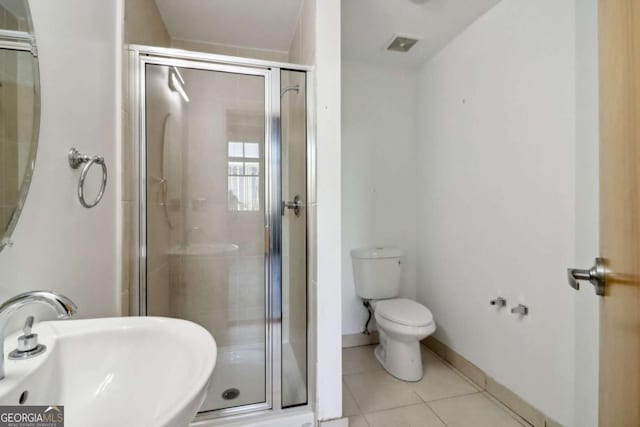 bathroom with sink, a shower with door, tile patterned floors, and toilet