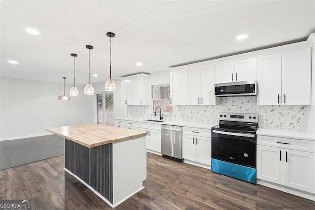 kitchen featuring wood counters, a center island, appliances with stainless steel finishes, pendant lighting, and white cabinets