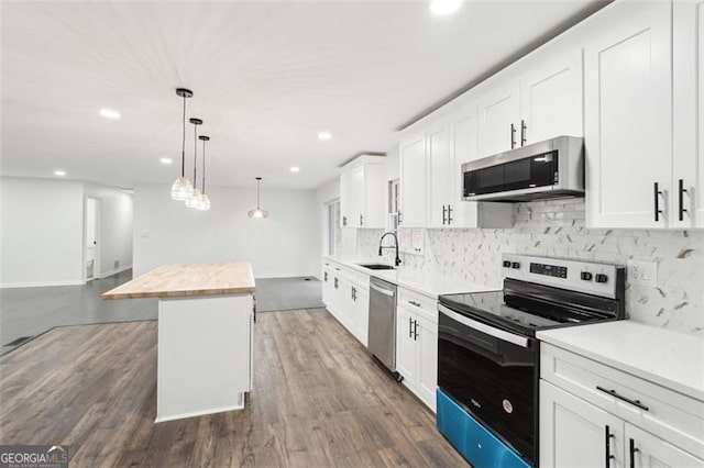 kitchen featuring butcher block countertops, white cabinetry, decorative light fixtures, a kitchen island, and stainless steel appliances