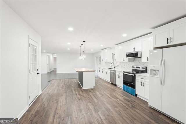 kitchen with pendant lighting, appliances with stainless steel finishes, a kitchen island, and white cabinets