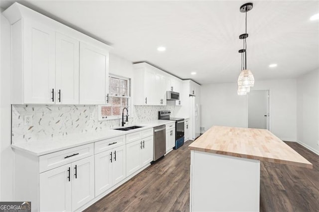 kitchen with sink, butcher block countertops, a kitchen island, stainless steel appliances, and white cabinets