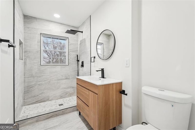 bathroom with vanity, toilet, and a tile shower