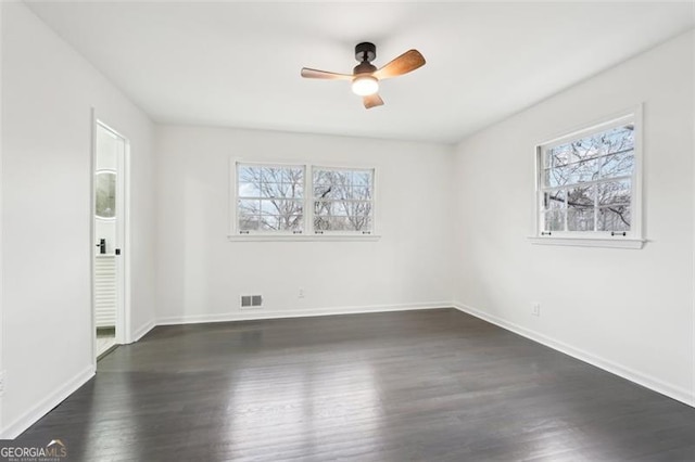 spare room featuring ceiling fan, dark wood-type flooring, and a healthy amount of sunlight