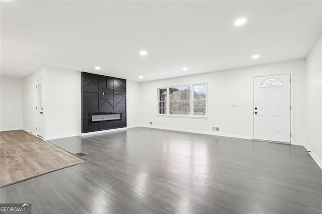 unfurnished living room featuring a large fireplace and dark hardwood / wood-style floors