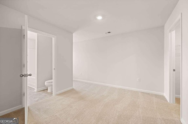 unfurnished bedroom with light carpet and connected bathroom