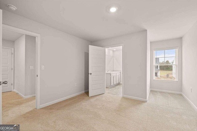 unfurnished bedroom with light colored carpet and ensuite bath