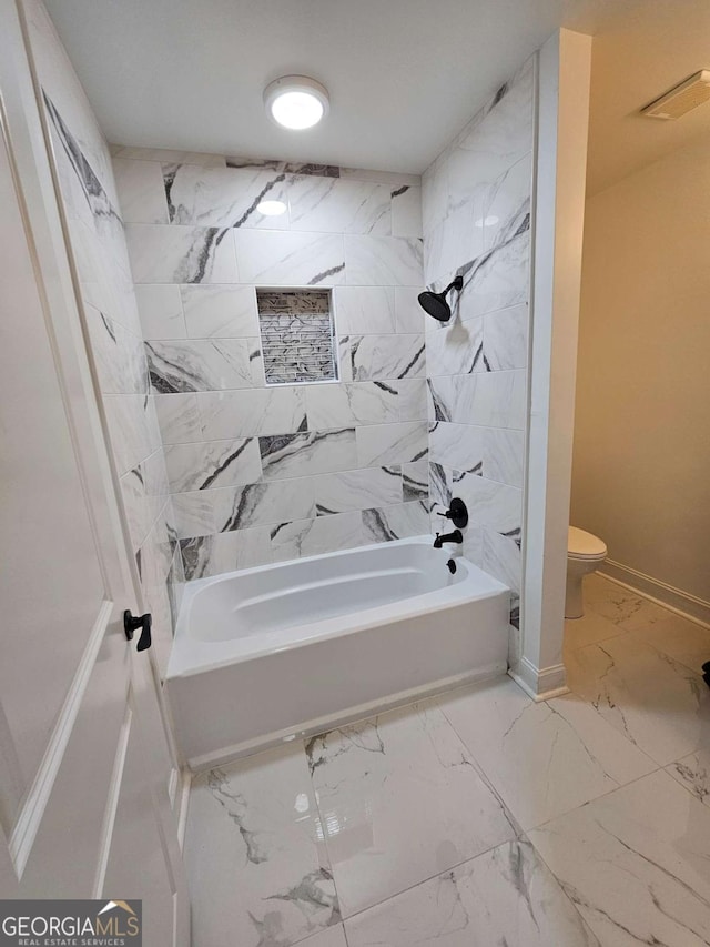 bathroom featuring toilet and tiled shower / bath combo