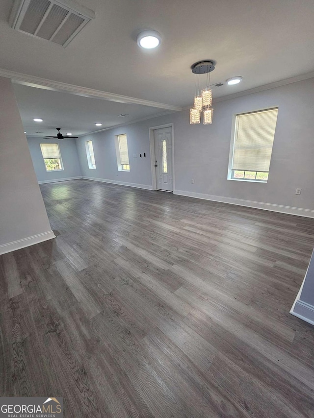 empty room with crown molding, dark hardwood / wood-style floors, and ceiling fan with notable chandelier